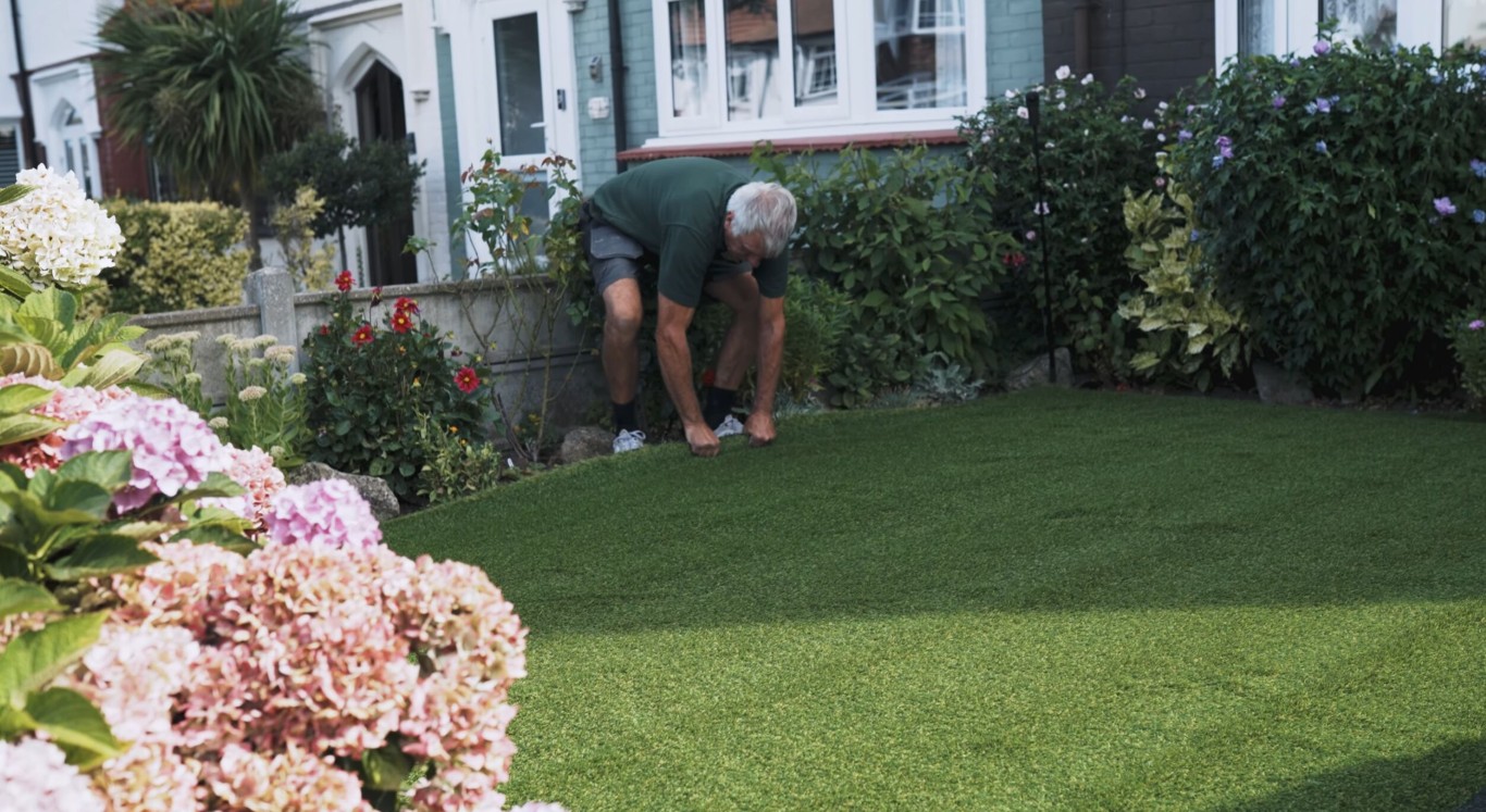 Pet-safe artificial grass with advanced drainage being inspected by homeowner in Delano, CA